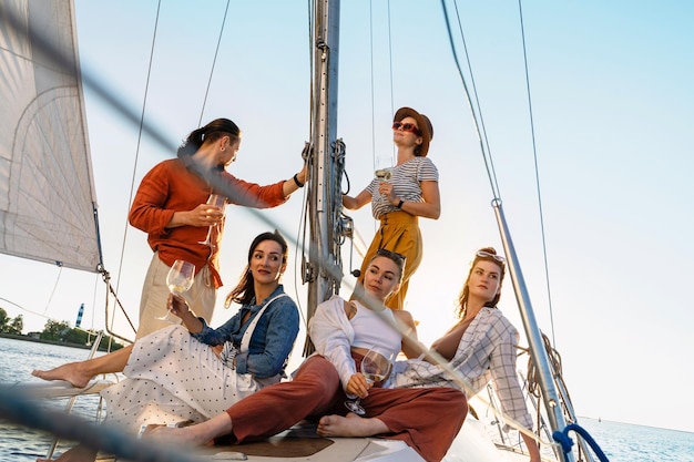 Un groupe d'amis heureux buvant du vin et se relaxant sur le voilier pendant la navigation en mer