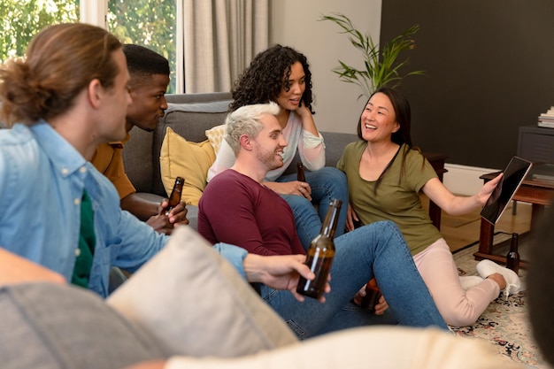 Photo groupe d'amis heureux et diversifiés, femmes et hommes, buvant de la bière ensemble et utilisant une tablette
