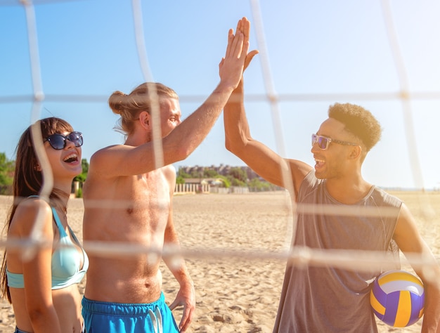 Groupe d'amis heureux jouant au beach-volley à la plage