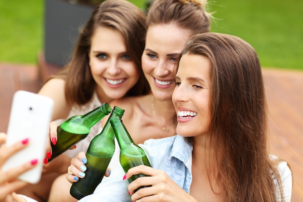 groupe d'amis heureux prenant une bière à l'extérieur et prenant un selfie