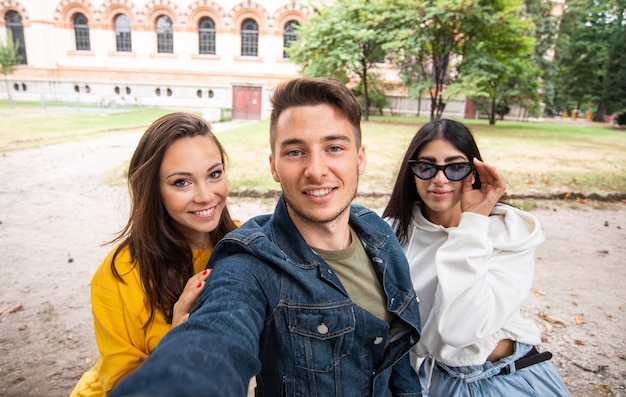 Groupe d'amis heureux prenant un selfie ensemble dans un parc