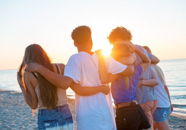 Groupe d'amis heureux s'amusant à Ocean Beach à l'aube