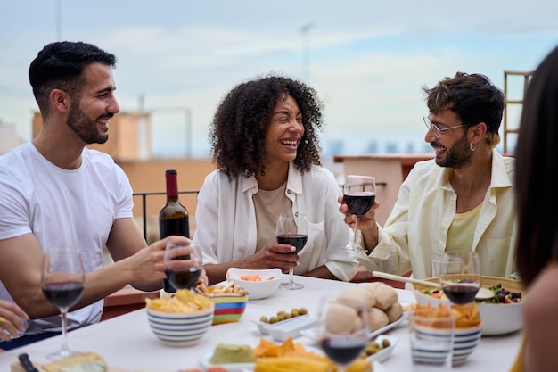 Un groupe d'amis jeunes et joyeux rassemblés pour un déjeuner, des gens du millénaire assis à table.