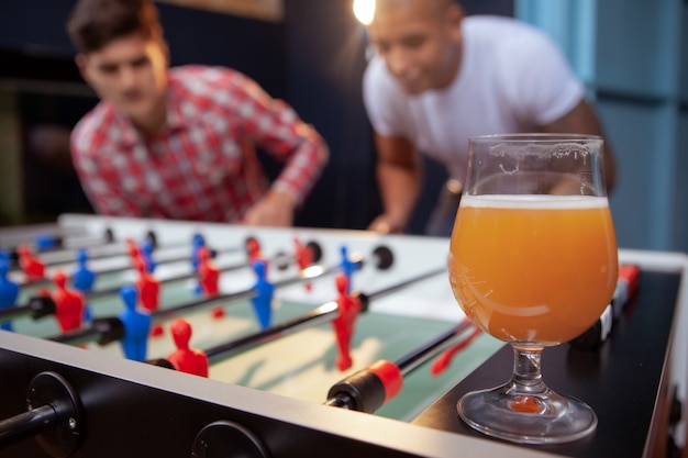 Groupe d'amis jouant au soccer sur table au pub de bière