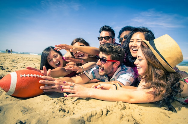 Groupe d'amis jouant avec le ballon de rugby essayant de le retirer du support