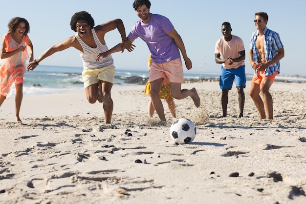 Photo un groupe d'amis joue au football sur la plage.