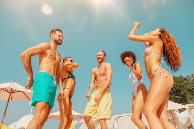 Groupe d'amis en maillot de bain dance music dans une piscine