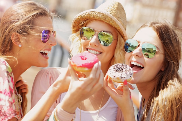 Groupe d'amis mangeant des beignets dans la ville