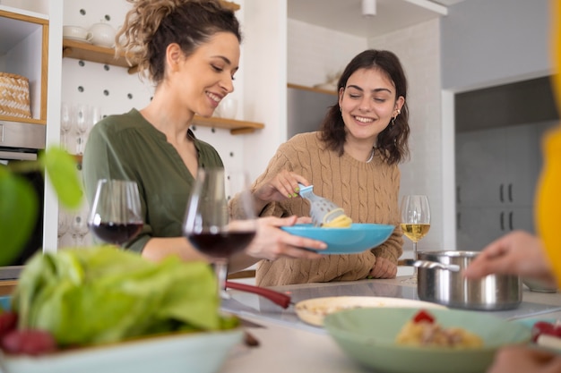 Photo groupe d'amis, manger des pâtes ensemble dans la cuisine