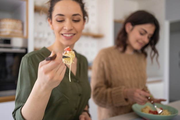 Photo groupe d'amis, manger des pâtes ensemble dans la cuisine