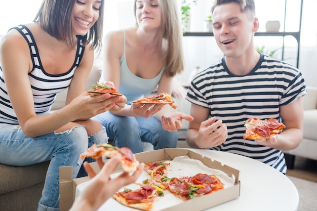 Groupe d'amis, manger de la pizza à l'intérieur