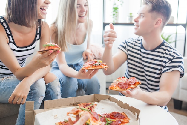 Groupe d'amis, manger de la pizza à l'intérieur