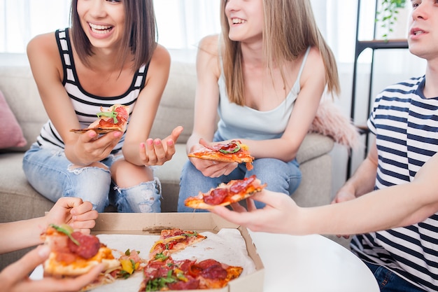 Groupe d'amis, manger de la pizza à l'intérieur