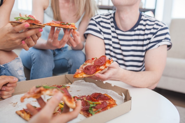 Groupe d'amis, manger de la pizza à l'intérieur