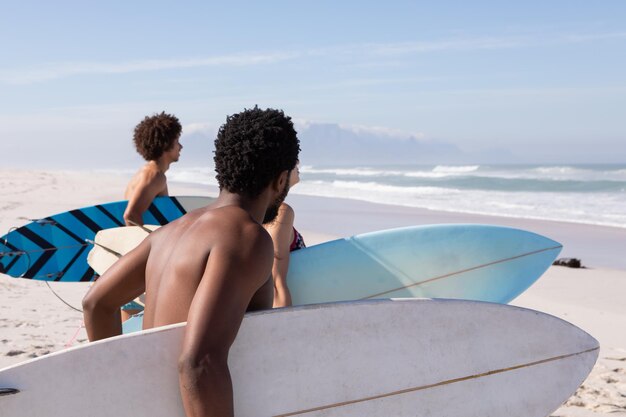 Photo un groupe d'amis marchant avec une planche de surf sur la plage