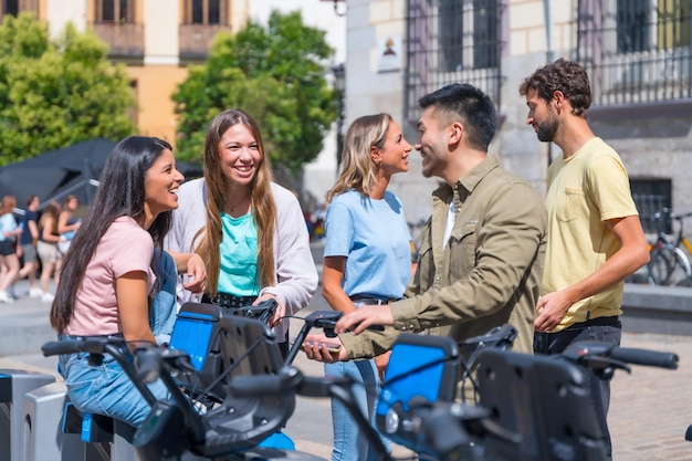 Groupe d'amis multiethniques dans la ville louant des vélos s'amusant un après-midi d'été