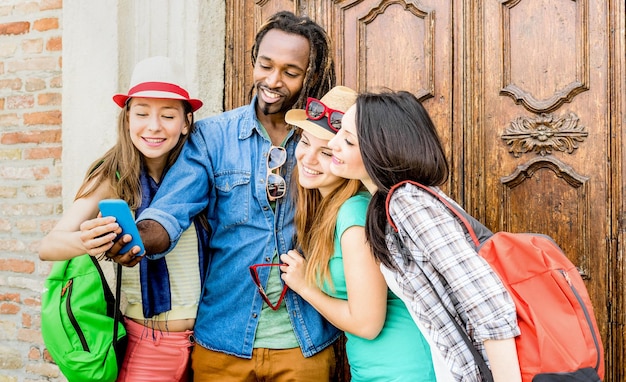 Photo groupe d'amis multiraciaux heureux prenant selfie avec un téléphone intelligent mobile jeunes hipsters accros au smartphone sur la communauté des réseaux sociaux concept technologique ton de filtre saturé vif