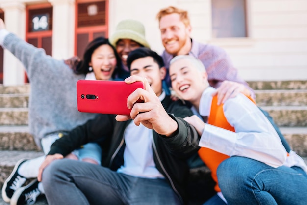 Groupe d'amis multiraciaux prenant un selfie ensemble tout en posant et souriant