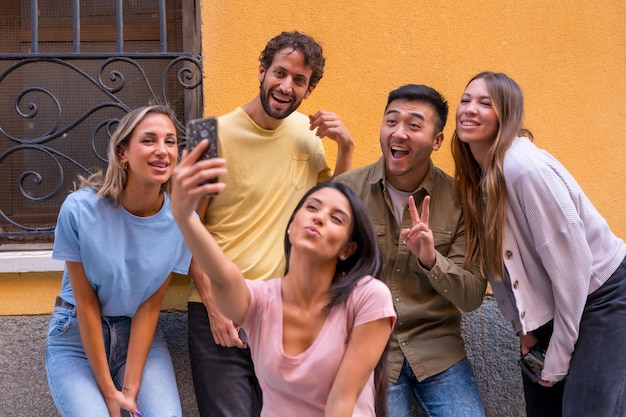 Groupe d'amis multiraciaux prenant un selfie souriant dans la ville