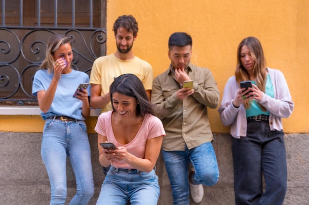 Groupe d'amis multiraciaux regardant souriant au téléphone dans la ville