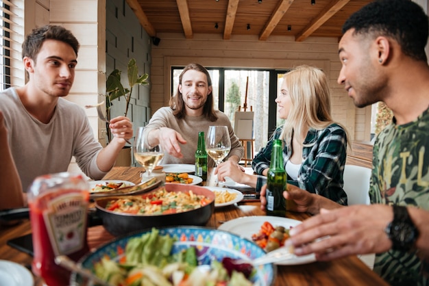 Groupe d'amis multiraciaux souriants heureux manger, boire et parler