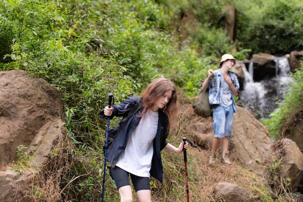 Un groupe d'amis par une journée ensoleillée dans la forêt Un jeune groupe de randonneurs avec un sac à dos et des bâtons de trekking