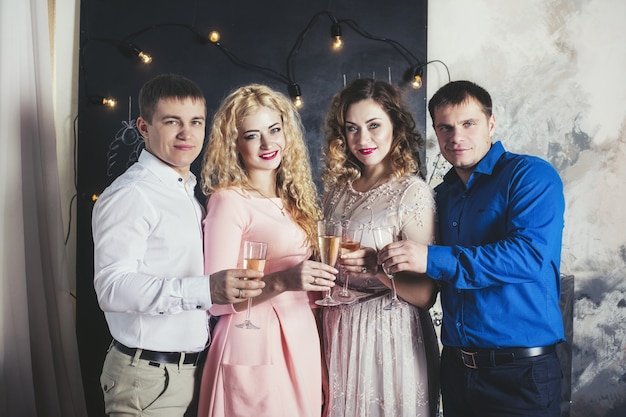 Groupe d'amis de personnes heureux avec de beaux sourires et du champagne pour fêter Noël ensemble à la maison