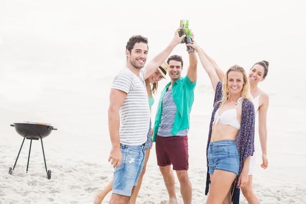 Groupe d'amis portant des bouteilles de bière sur la plage