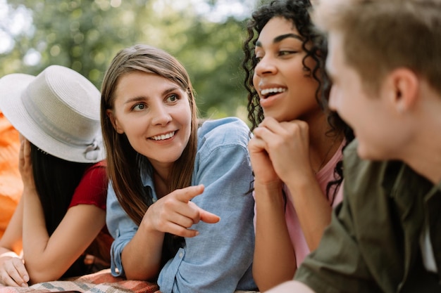 Un groupe d'amis positifs se rencontrent à une fête d'anniversaire allongés sur l'herbe à parler