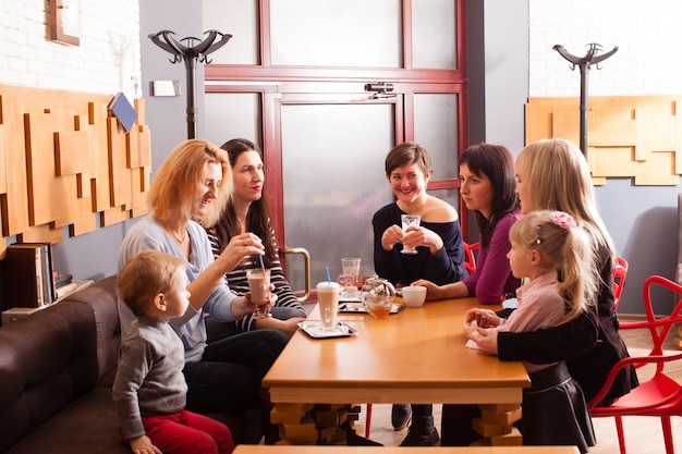 Un groupe d'amis prenant les boissons avec les enfants assis à proximité. Prise de vue horizontale à l'intérieur.