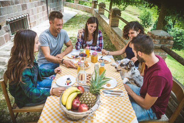 Groupe d'amis prenant le petit déjeuner dans une ferme