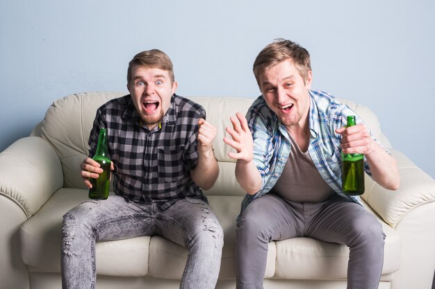 Groupe d'amis regardant le sport ensemble, les jeunes hommes boivent de la bière