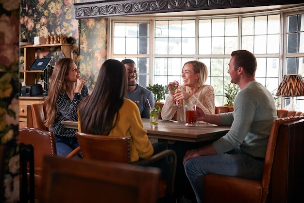 Groupe d'amis réunis pour prendre un verre à midi dans un pub anglais traditionnel