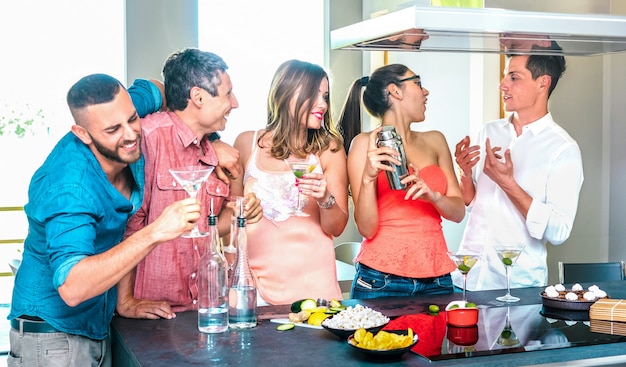 Groupe d'amis s'amusant au bar à cocktails de la maison avec apéritif avant le dîner à l'heure de l'happy hour