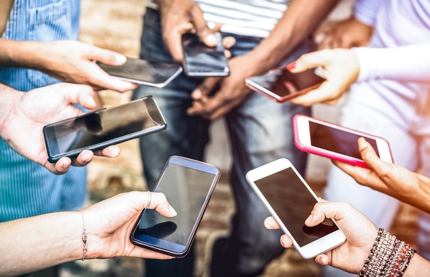 Photo groupe d'amis s'amusant ensemble à l'aide de smartphones