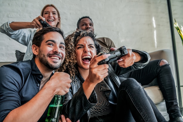 Groupe d'amis s'amusant en jouant à des jeux vidéo ensemble à la maison. Notion d'amis.