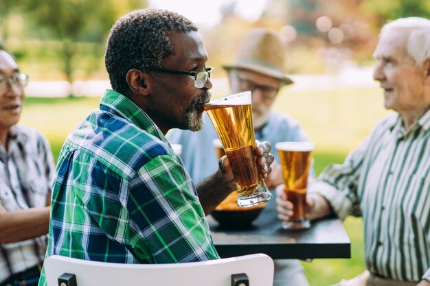 Groupe d'amis seniors buvant une bière au parc. Concepts de style de vie sur l'ancienneté et le troisième âge