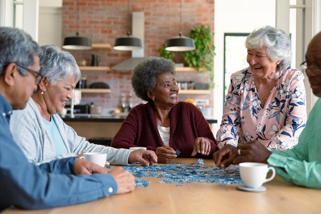 Groupe d'amis seniors, hommes et femmes, faisant des puzzles à la maison