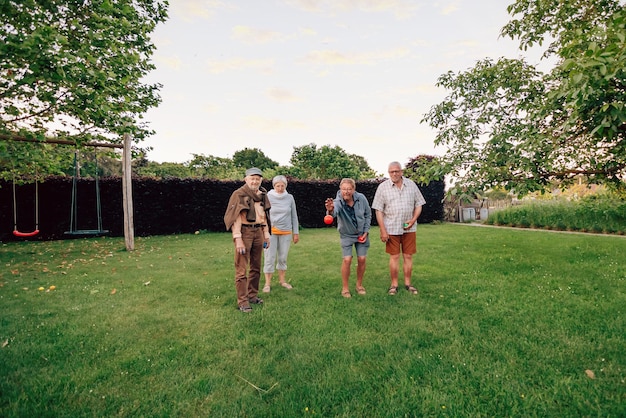 Groupe d'amis seniors jouant à la pétanque dans le parc