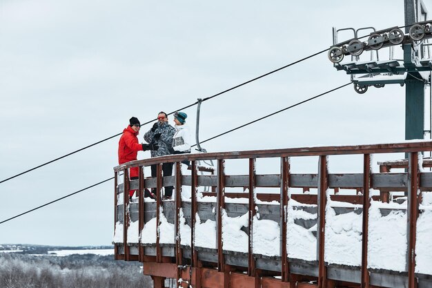 Un groupe d'amis skieurs sur la montagne se repose et boit du café dans un thermos sur le fond de la remontée mécanique.