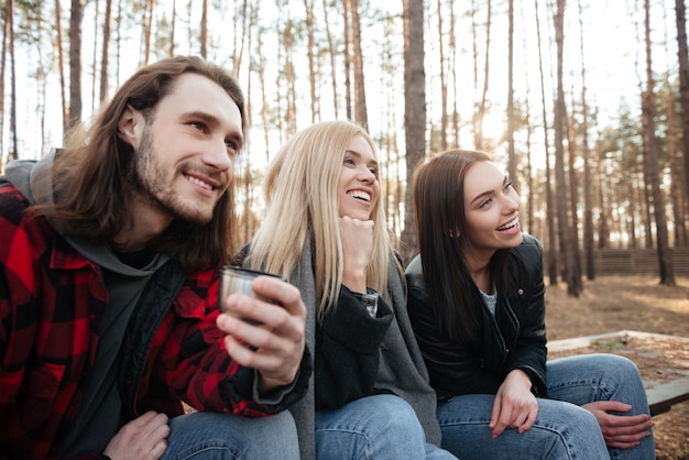 Groupe d'amis souriant assis à l'extérieur dans la forêt