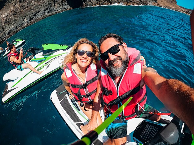 Groupe d'amis de touristes s'amusent avec jet sky sur l'eau de l'océan bleu