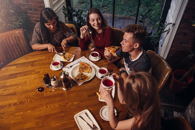 groupe d'amis en train de dîner à table ronde parler et sourire