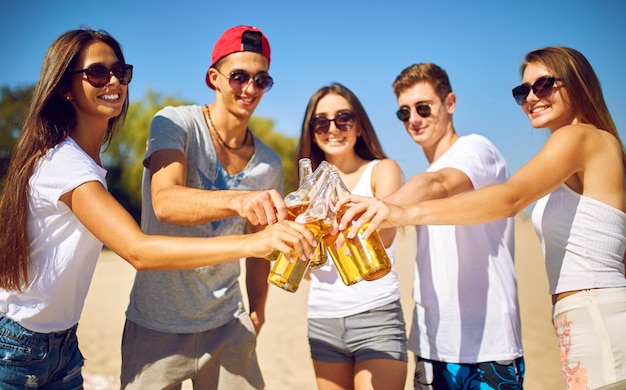 Groupe d'amis traînant avec de la bière à la plage Excellent temps ensoleillé Belles figures