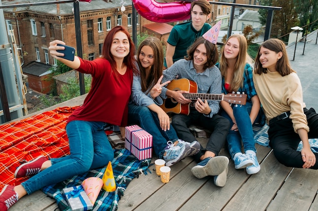 Groupe d'anniversaire selfie sur un toit. Amis prenant des photos à partager sur les réseaux sociaux. Mode de vie des jeunes bff