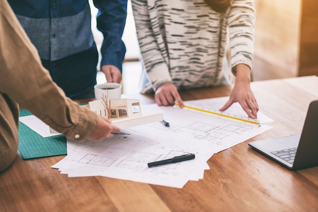 Groupe d'un architecte travaillant et mesurant l'échelle d'un modèle de masse sur une table au bureau