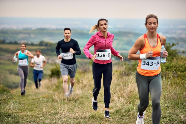 Groupe d'athlètes courant un marathon dans la nature L'accent est mis sur une femme en chemise rose