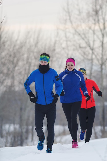 Groupe d'athlètes faisant du jogging dans la forêt d'hiver, concept de sport et de loisirs