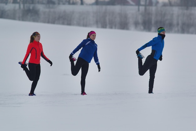 Groupe d'athlètes s'échauffant et s'étirant avant l'exercice dans la forêt d'hiver, concept de sport et de loisirs