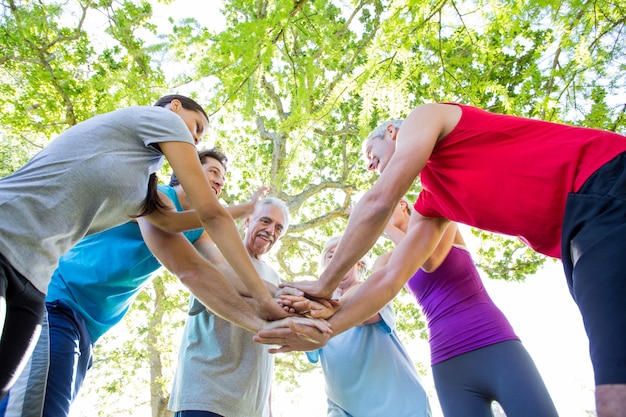 Groupe athlétique heureux mettant leurs mains ensemble